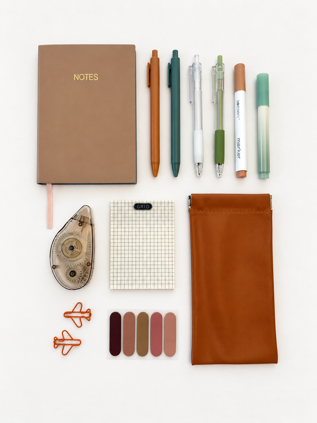Cedar Grove stationery collection with brown notebook, six writing tools, grid notepad, correction tape, pen pouch, paper clips, and color swatches.
