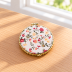Boutique floral compact mirror with a padded exterior, gold-tone trim, and double mirrors. Product photo 4 of 4.