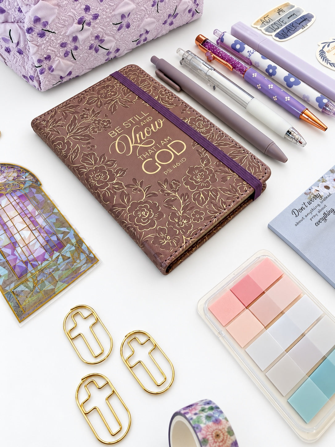 Close-up of Be Still gold embossed Scripture journal with coordinated purple pens and page tabs