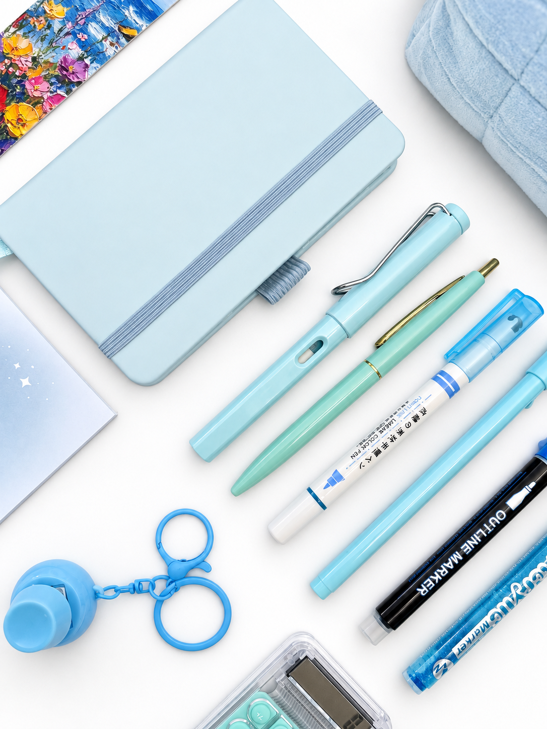 Close-up of the Cotton Candy blue kids stationery collection showing the A6 journal, coordinating writing tools, calculator, sticky notes, fidget keychain, bookmark, and pencil case.
