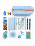 Cotton Candy blue kids stationery collection flat lay with pencil case, A6 journal, writing tools, calculator, sticky notes, tape roller, fidget keychain, bookmark, and stickers.