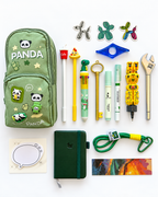 Into the Wild Premier Kids Collection flat lay with green panda pencil case, A7 pocket journal, novelty writing tools, decorative notepad, bookmark, stickers, page holder, and green keychain.