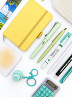 Close-up of the Lemon Lime yellow and green kids stationery collection showing the A6 journal, coordinating writing tools, calculator, sticky notes, fidget keychain, bookmark, and pencil case.