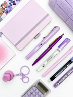 Close-up of the Sugar Plum purple kids stationery collection showing the A6 journal, coordinating writing tools, calculator, sticky notes, fidget keychain, bookmark, and pencil case.