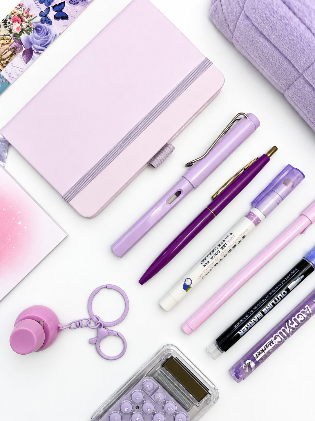 Close-up of the Sugar Plum purple kids stationery collection showing the A6 journal, coordinating writing tools, calculator, sticky notes, fidget keychain, bookmark, and pencil case.
